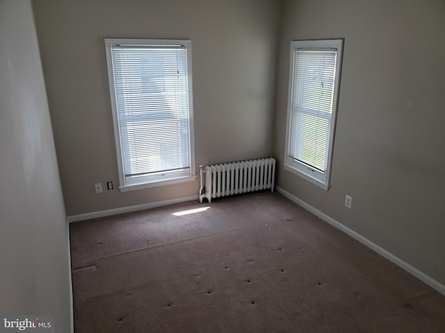 carpeted spare room featuring plenty of natural light and radiator heating unit