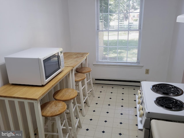 kitchen with baseboard heating, a kitchen bar, and white appliances