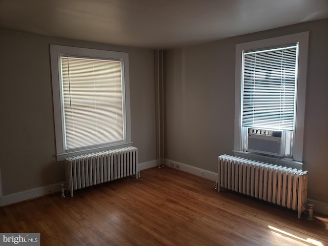 empty room featuring wood-type flooring, radiator, and cooling unit