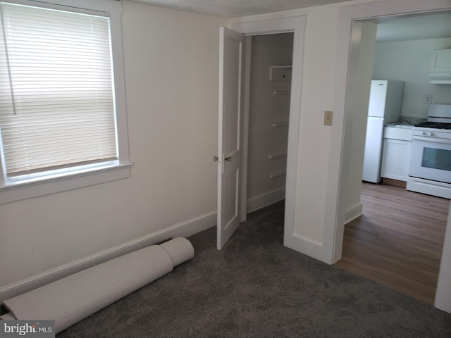 interior space featuring dark carpet, a textured ceiling, and white fridge