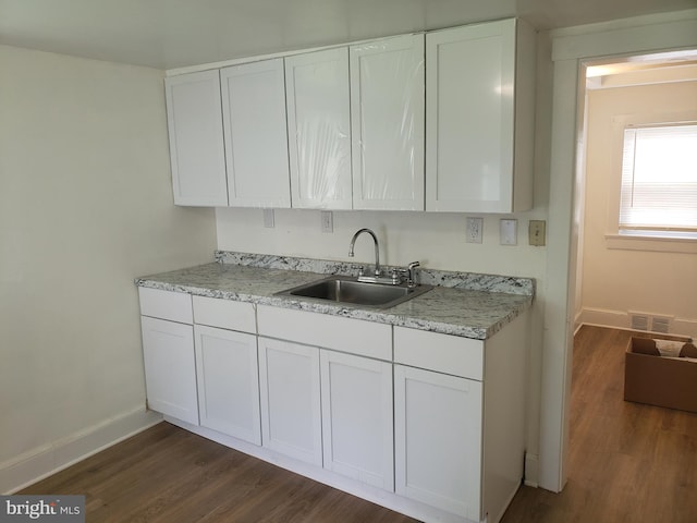 kitchen featuring dark wood-type flooring, sink, and white cabinetry