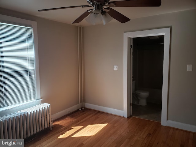 spare room featuring ceiling fan, radiator, and light hardwood / wood-style flooring