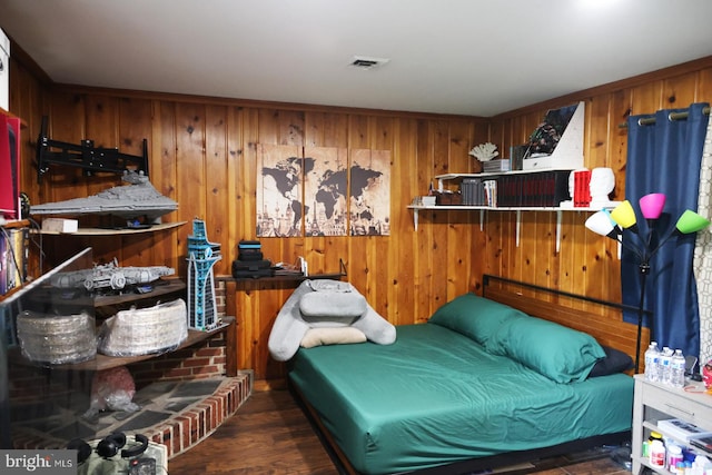 bedroom featuring dark hardwood / wood-style flooring and wooden walls