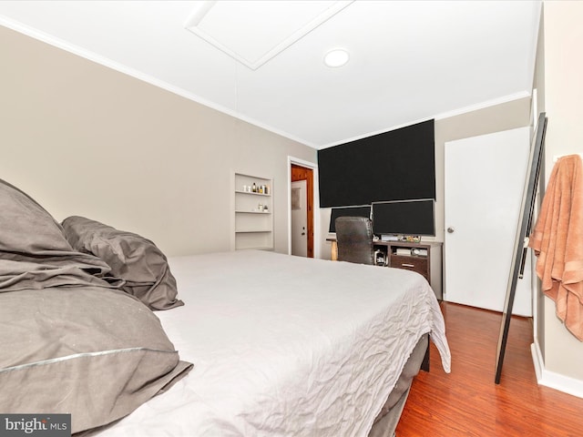 bedroom featuring wood-type flooring, ornamental molding, and a closet