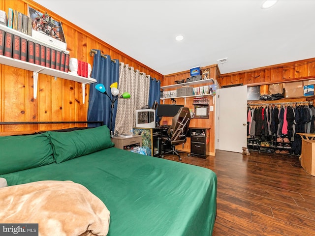 bedroom with wood walls, a closet, dark hardwood / wood-style floors, and ornamental molding