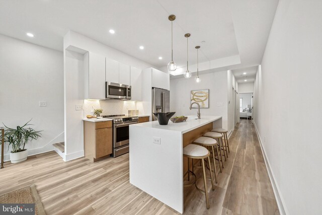 2015 13th St NW Unit 3, Washington, DC 20009 - kitchen with a breakfast bar area, white cabinetry, stainless steel appliances, and light wood-style flooring