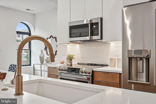 2015 13th St NW Unit 3, Washington, DC 20009 - kitchen with tasteful backsplash, brown cabinets, light countertops, appliances with stainless steel finishes, and visible vents