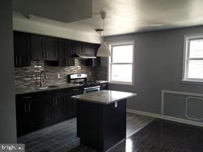 kitchen featuring dark wood-type flooring, backsplash, a kitchen island, stainless steel range oven, and sink