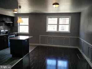 kitchen with plenty of natural light, dark hardwood / wood-style floors, electric range, and a kitchen island