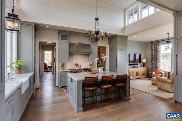 kitchen with hanging light fixtures, a kitchen island, wood-type flooring, extractor fan, and a kitchen breakfast bar