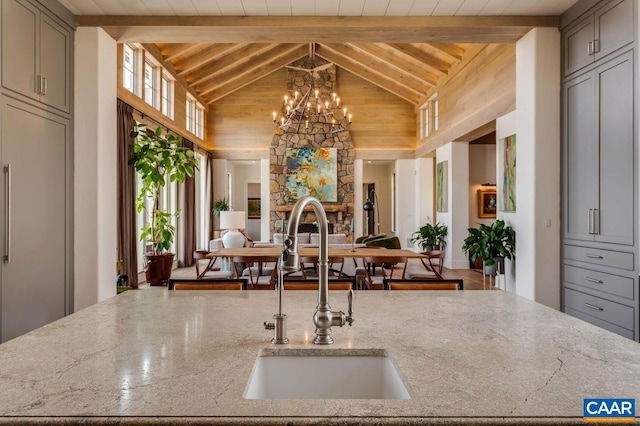 kitchen featuring high vaulted ceiling, beamed ceiling, hardwood / wood-style floors, sink, and a notable chandelier