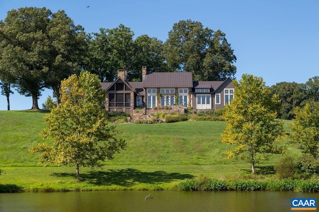 rear view of house with a yard and a water view