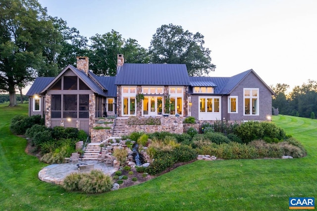 back house at dusk with a sunroom and a yard