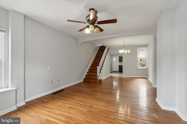 spare room featuring ceiling fan with notable chandelier and light hardwood / wood-style floors