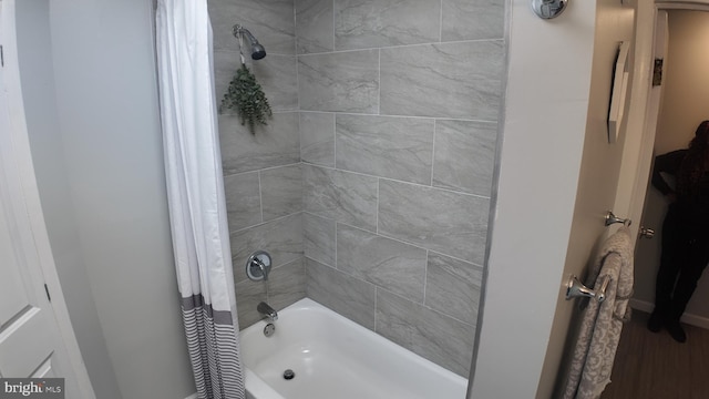 bathroom with hardwood / wood-style flooring and shower / bathtub combination with curtain