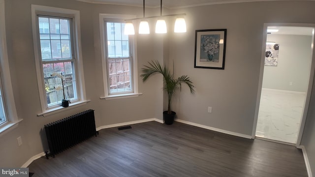 spare room with ornamental molding, radiator, and dark wood-type flooring