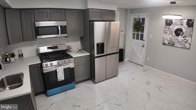 kitchen with pendant lighting, sink, appliances with stainless steel finishes, and tasteful backsplash