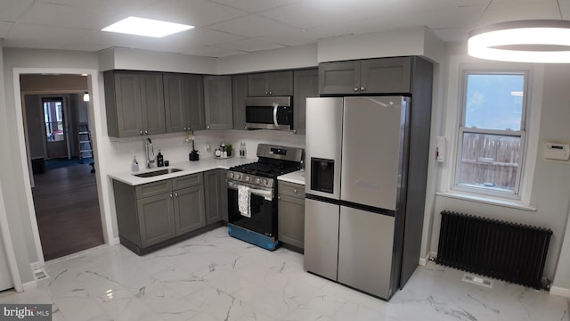 kitchen with a paneled ceiling, sink, radiator heating unit, and stainless steel appliances