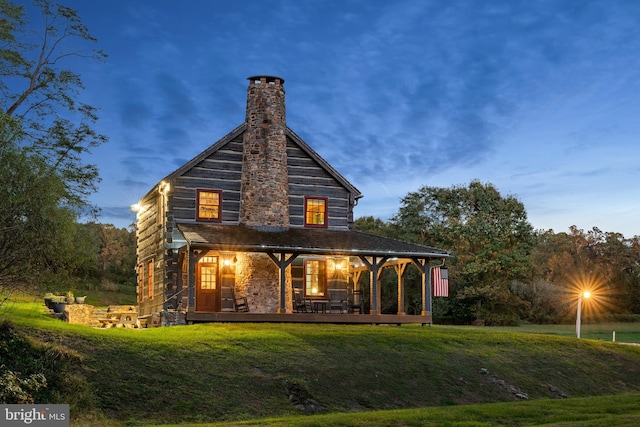 back house at dusk featuring a yard