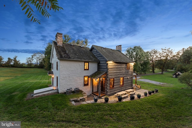 back house at dusk with cooling unit and a yard