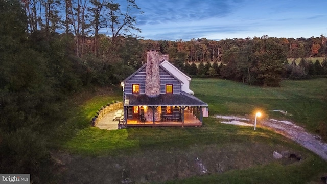 back house at dusk featuring a yard