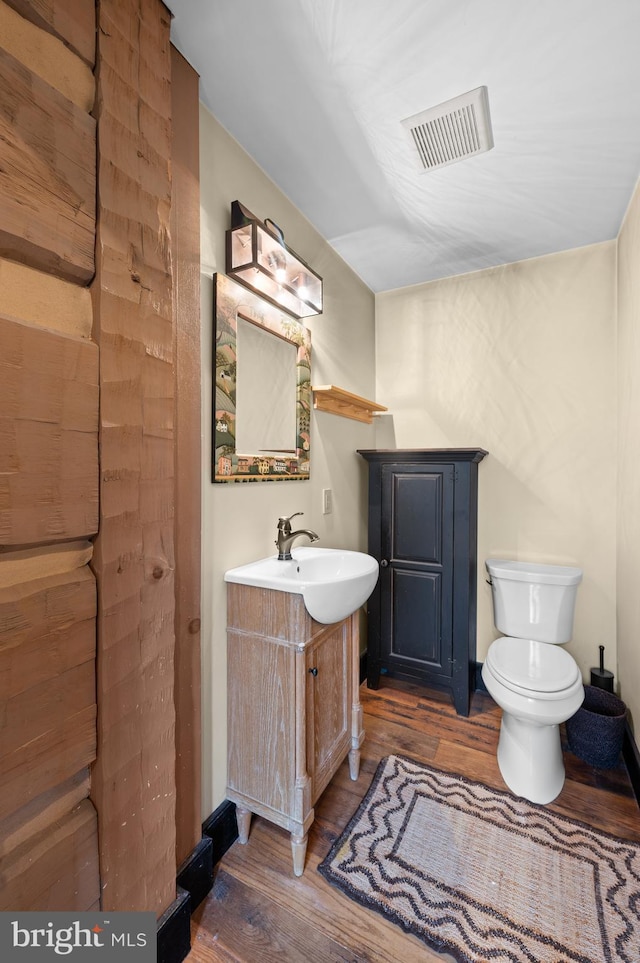 bathroom with hardwood / wood-style floors, vanity, and toilet