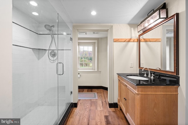 bathroom featuring wood-type flooring, walk in shower, and vanity