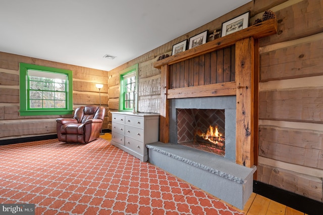 sitting room with hardwood / wood-style flooring, wooden walls, and a wealth of natural light