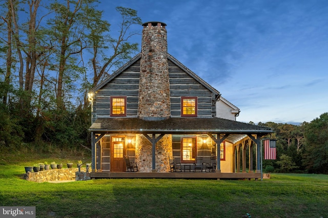 back house at dusk featuring a lawn and a wooden deck