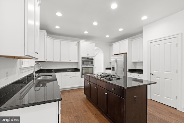 kitchen featuring wood-type flooring, a kitchen island, appliances with stainless steel finishes, sink, and white cabinets