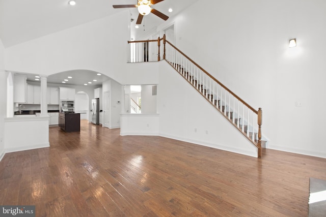 unfurnished living room featuring ceiling fan, dark hardwood / wood-style floors, and high vaulted ceiling