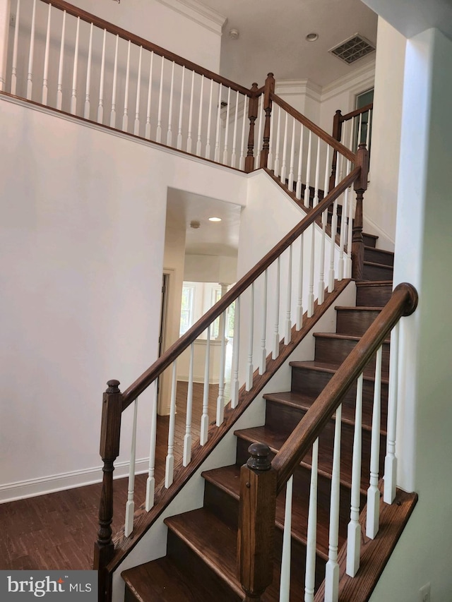 stairs featuring wood-type flooring and crown molding