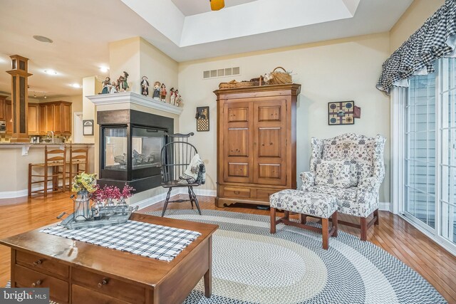 sitting room with a multi sided fireplace and light wood-type flooring