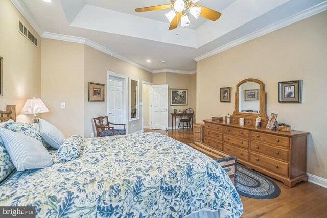 bedroom featuring ceiling fan, a raised ceiling, hardwood / wood-style flooring, and crown molding