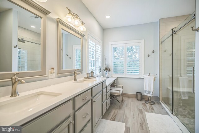 bathroom with wood-type flooring, vanity, and a shower with shower door