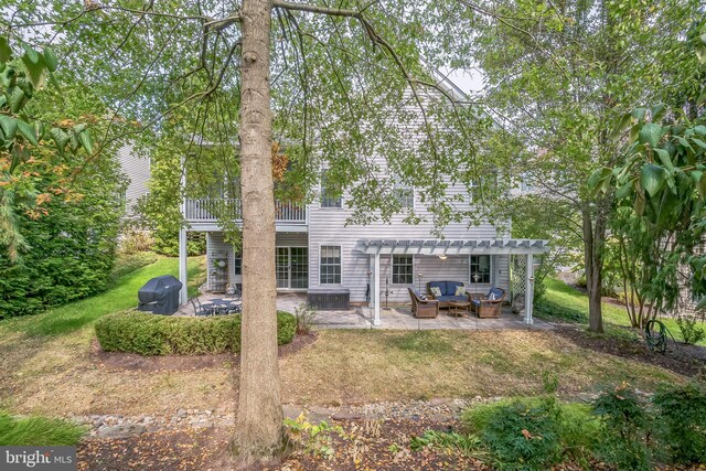 back of house featuring a balcony, a pergola, a patio area, and a lawn