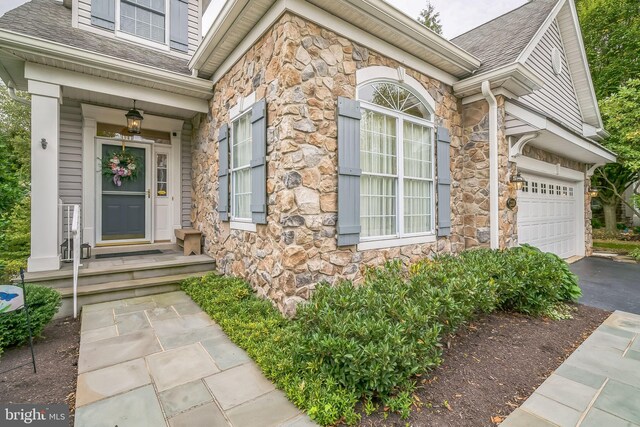 view of exterior entry with a garage and covered porch