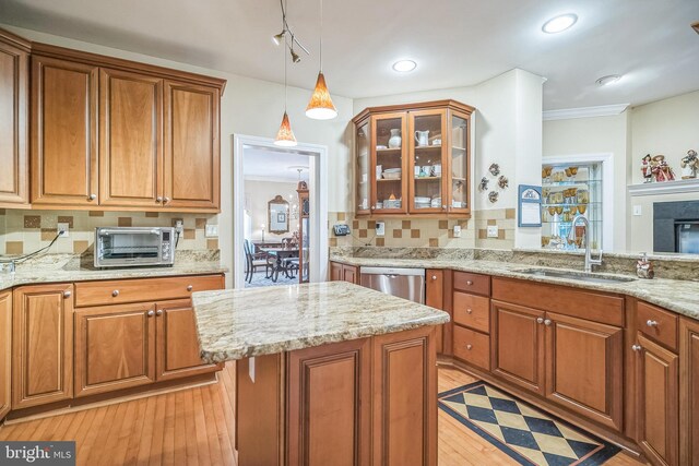 kitchen with hanging light fixtures, sink, stainless steel dishwasher, light hardwood / wood-style flooring, and backsplash