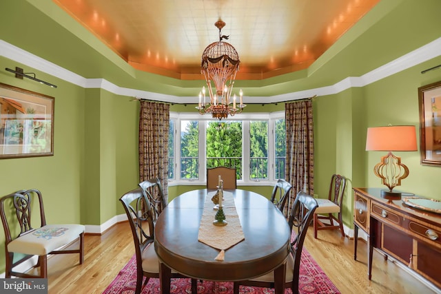 dining space featuring light hardwood / wood-style flooring, a chandelier, and a raised ceiling