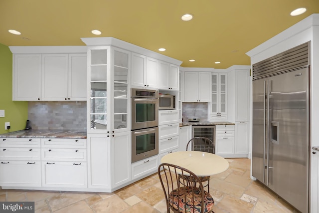 kitchen with tasteful backsplash, wine cooler, appliances with stainless steel finishes, and white cabinets