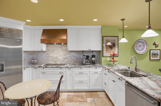 kitchen featuring appliances with stainless steel finishes, white cabinetry, pendant lighting, premium range hood, and sink