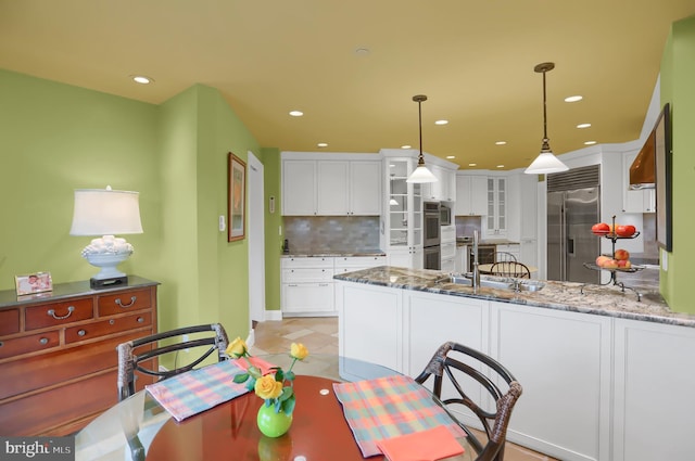 kitchen with white cabinetry, backsplash, a peninsula, and appliances with stainless steel finishes