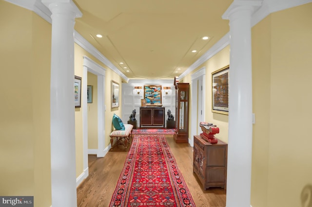 hallway with decorative columns, wood finished floors, recessed lighting, and crown molding