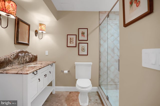 full bath with toilet, vanity, a stall shower, and baseboards