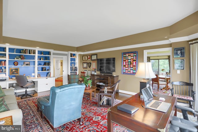 living room featuring baseboards, wood finished floors, and built in features