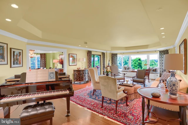 living room with crown molding, wood-type flooring, and a tray ceiling