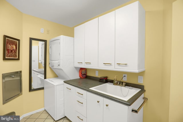 washroom featuring stacked washer / drying machine, baseboards, a sink, light tile patterned flooring, and cabinet space