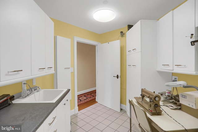 kitchen featuring sink, light tile patterned floors, and white cabinets