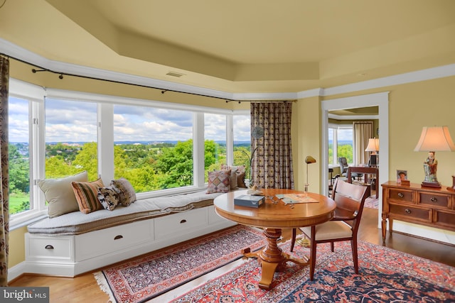 dining area with light hardwood / wood-style flooring and a tray ceiling