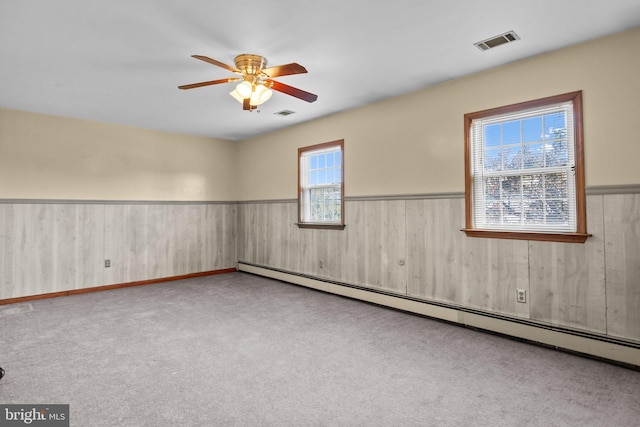 empty room with a baseboard heating unit, ceiling fan, and light colored carpet